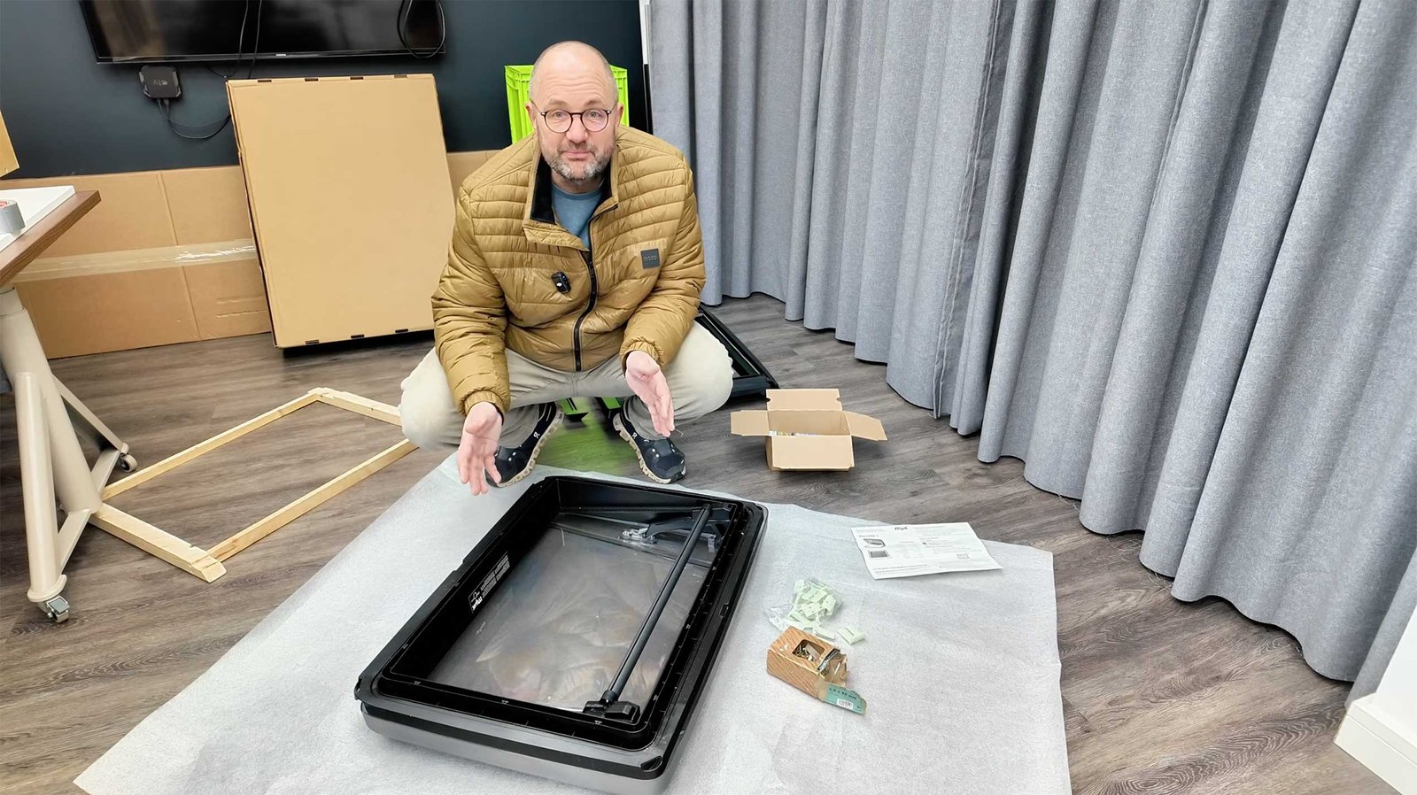 Mann kniet neben einem Dachfenster und einem Holzrahmen