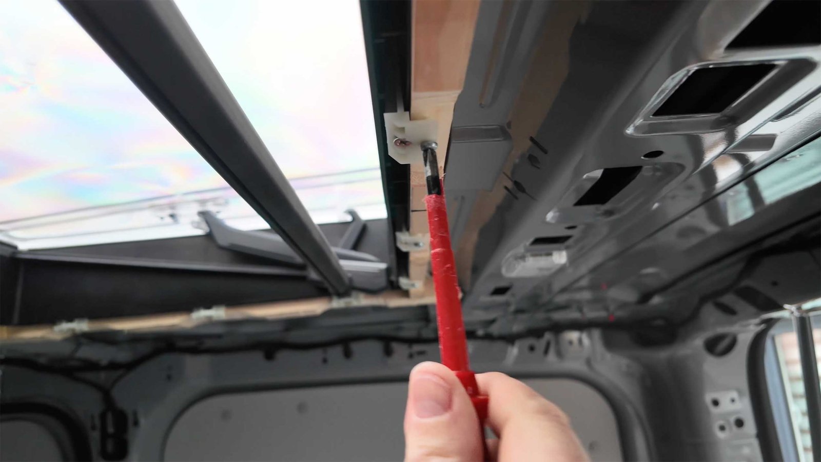 Arbeiten mit einer Säge an einem Metallsteg unter dem Fahrzeugdach