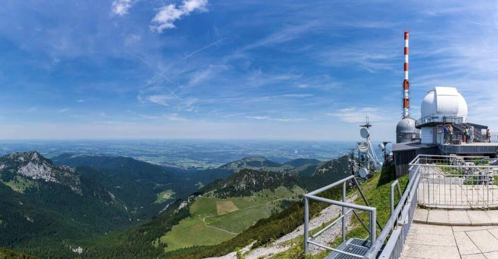 Aussichtsplattform und Wetterstation vor einem weiten Bergpanorama